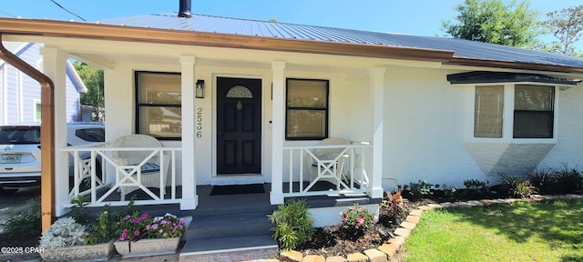 view of front of property featuring covered porch, metal roof, and stucco siding