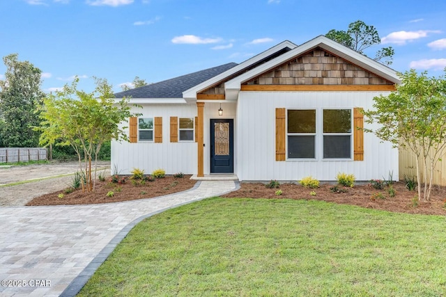 view of front of property featuring a front yard, fence, and a shingled roof