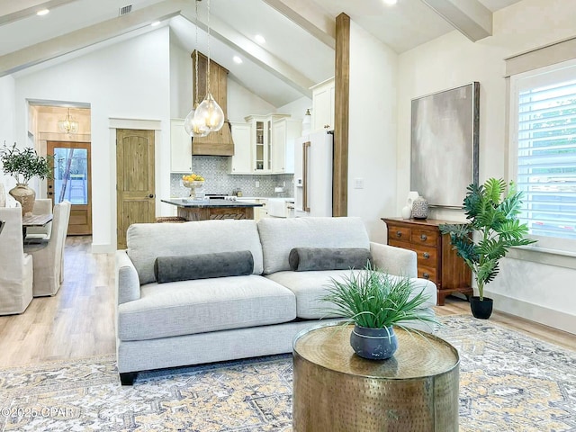 living area featuring light wood-type flooring, beamed ceiling, high vaulted ceiling, and a notable chandelier