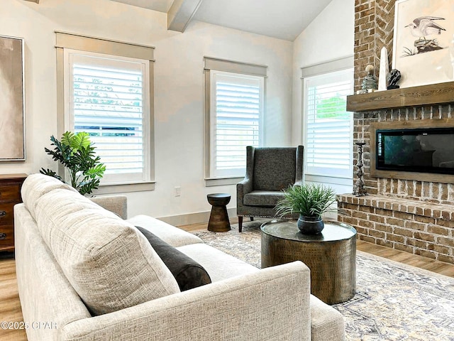 living area with a fireplace, lofted ceiling with beams, wood finished floors, and baseboards