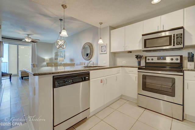 kitchen featuring light tile patterned floors, a peninsula, white cabinets, stainless steel appliances, and a sink