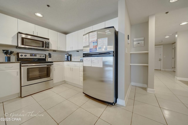 kitchen with white cabinets, light tile patterned flooring, tasteful backsplash, and stainless steel appliances