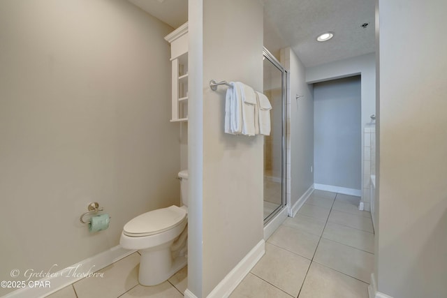 bathroom featuring tile patterned floors, a shower stall, toilet, and baseboards