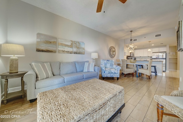 living room featuring wood finish floors, visible vents, baseboards, and a ceiling fan