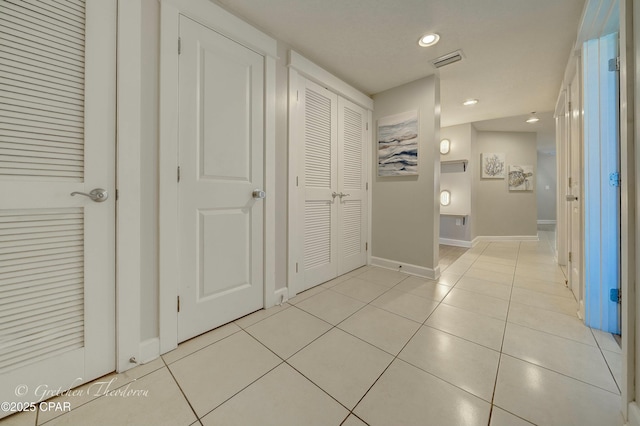 hallway featuring light tile patterned floors, visible vents, recessed lighting, and baseboards