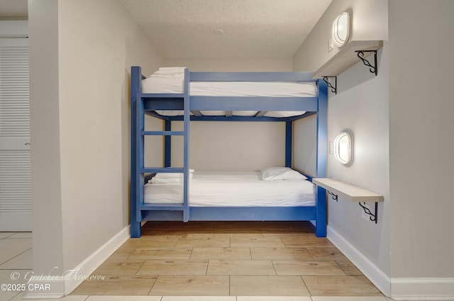 unfurnished bedroom with a textured ceiling, baseboards, and wood tiled floor