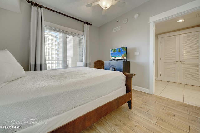 bedroom with ceiling fan, visible vents, baseboards, and wood finished floors