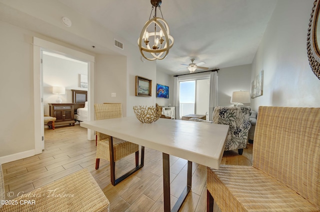 dining room with ceiling fan with notable chandelier, baseboards, visible vents, and wood tiled floor