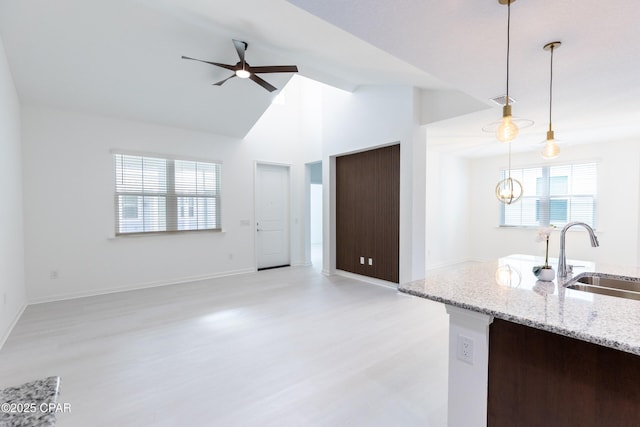 kitchen with ceiling fan, decorative light fixtures, open floor plan, light wood-type flooring, and a sink