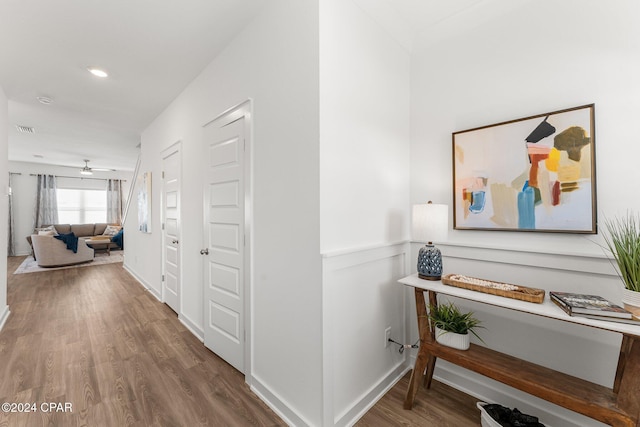 hallway with wood finished floors, visible vents, and baseboards