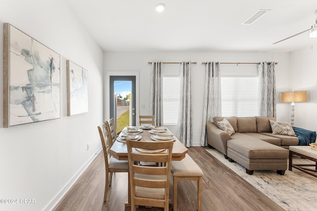 dining space with wood finished floors, visible vents, and baseboards