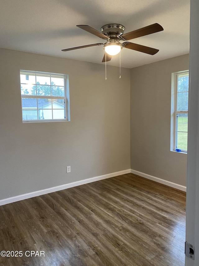 empty room featuring a wealth of natural light, dark wood-style floors, and baseboards