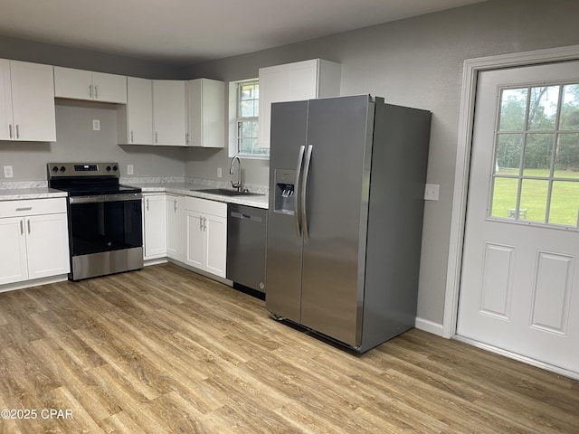 kitchen featuring a sink, light wood-style floors, white cabinetry, and stainless steel appliances