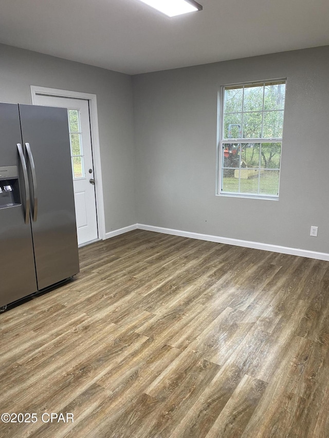 empty room featuring a wealth of natural light, baseboards, and wood finished floors