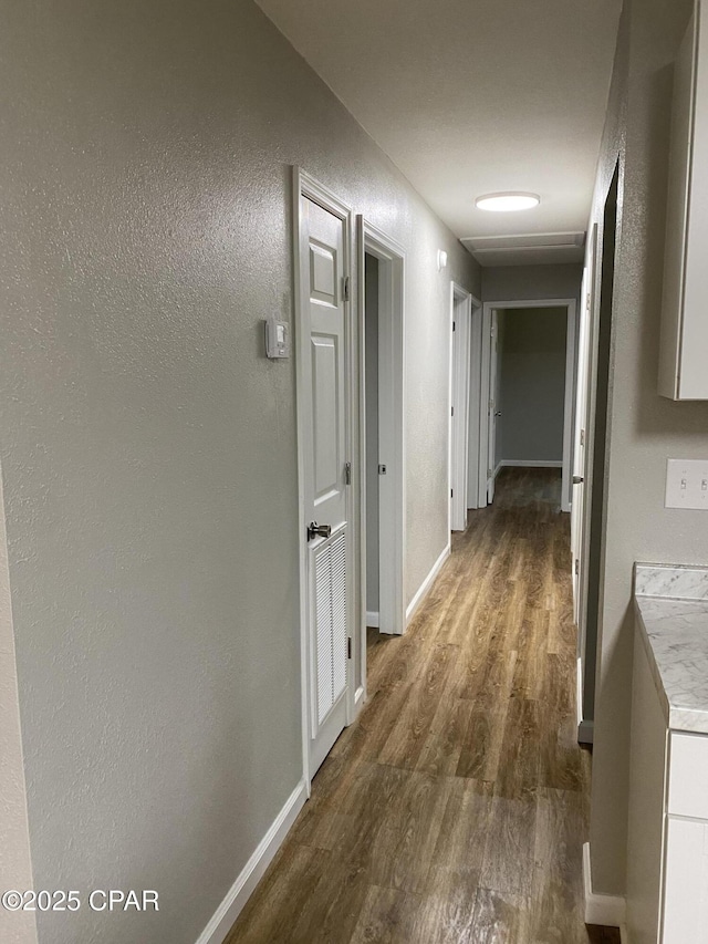 hall featuring baseboards and dark wood-type flooring