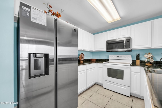 kitchen with a sink, appliances with stainless steel finishes, light tile patterned flooring, and white cabinets