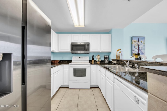 kitchen with a sink, appliances with stainless steel finishes, light tile patterned flooring, and white cabinets