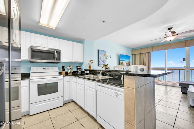 kitchen with a sink, white cabinetry, white appliances, a peninsula, and light tile patterned flooring