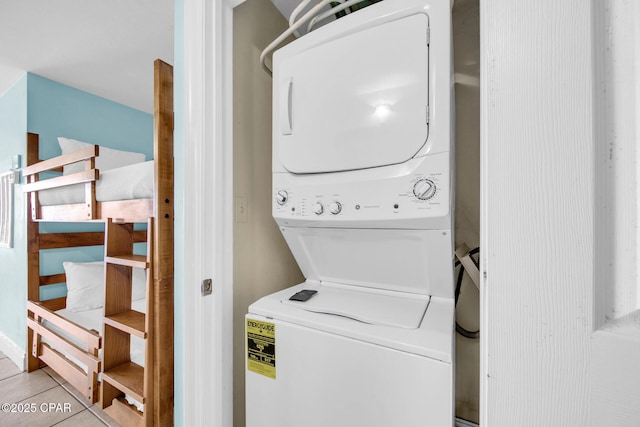 washroom with light tile patterned floors and stacked washer and dryer