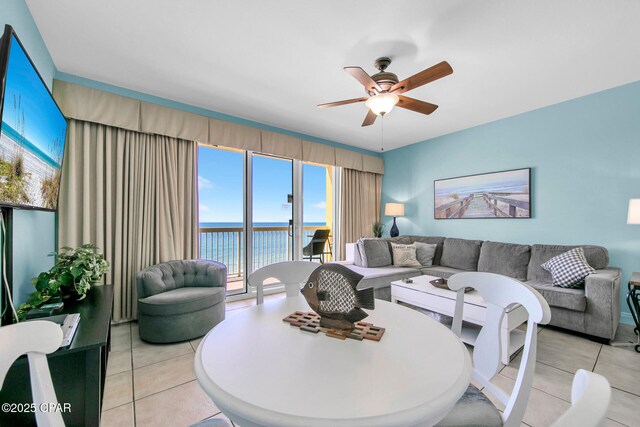 living area featuring light tile patterned flooring, ceiling fan, and a water view