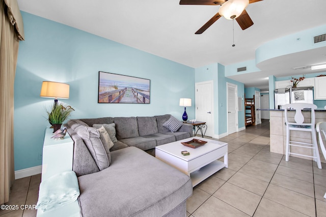 living area with light tile patterned flooring, baseboards, and a ceiling fan