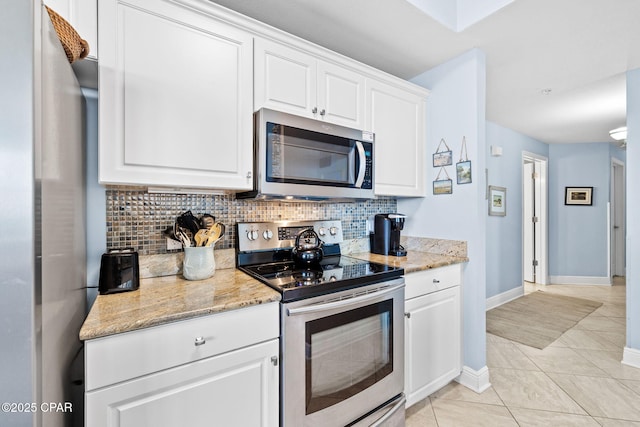 kitchen featuring backsplash, white cabinetry, stainless steel appliances, light tile patterned floors, and light stone countertops