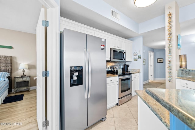 kitchen with visible vents, light stone counters, decorative backsplash, appliances with stainless steel finishes, and white cabinetry