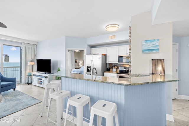 kitchen featuring visible vents, light stone counters, light tile patterned floors, decorative backsplash, and appliances with stainless steel finishes