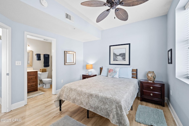 bedroom featuring visible vents, light wood-style flooring, a ceiling fan, ensuite bath, and baseboards