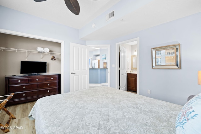 bedroom with visible vents, connected bathroom, wood finished floors, a closet, and a ceiling fan