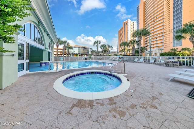 community pool with a patio and a hot tub