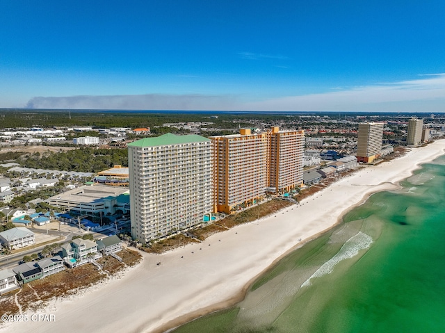 drone / aerial view featuring a water view, a city view, and a beach view