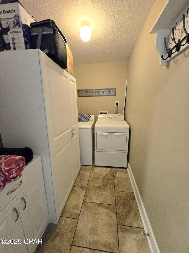 laundry area featuring washer and dryer, baseboards, cabinet space, and a textured ceiling