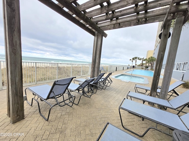 view of patio / terrace with a beach view, a community pool, a pergola, and a water view