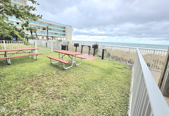 view of yard with a view of the beach, fence, and a water view