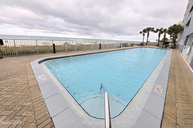 community pool featuring a water view, a patio, and fence