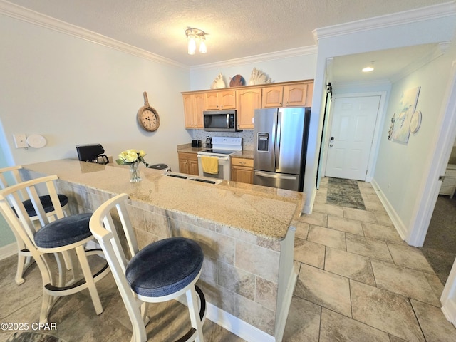 kitchen with a breakfast bar area, a peninsula, ornamental molding, appliances with stainless steel finishes, and a textured ceiling