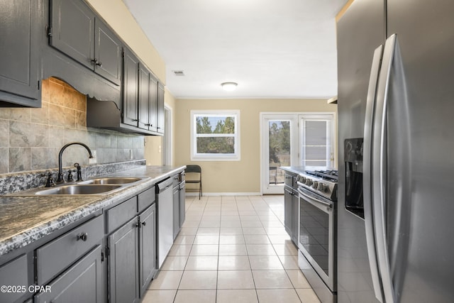 kitchen with tasteful backsplash, light tile patterned floors, gray cabinets, stainless steel appliances, and a sink