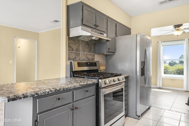 kitchen featuring light tile patterned floors, gray cabinets, under cabinet range hood, appliances with stainless steel finishes, and tasteful backsplash