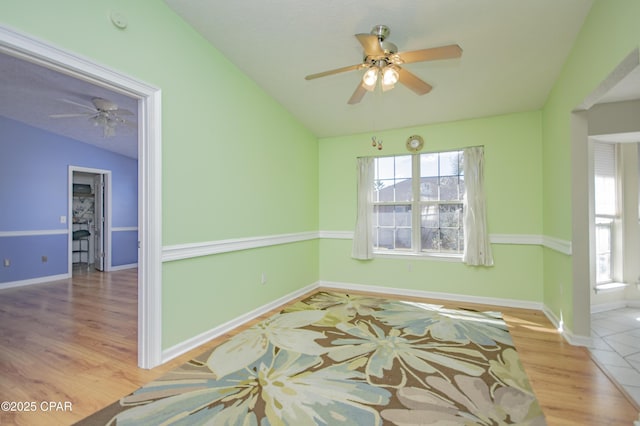 spare room featuring lofted ceiling, wood finished floors, and a ceiling fan