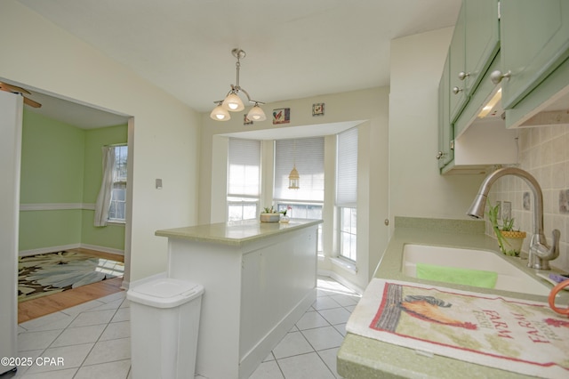 kitchen with a sink, green cabinets, light tile patterned flooring, and light countertops