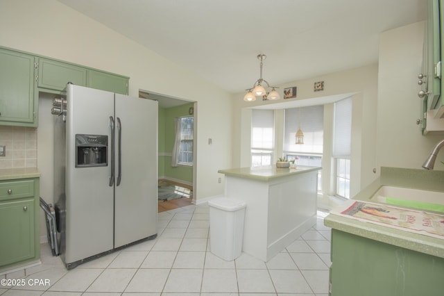 kitchen with green cabinets, light tile patterned floors, white fridge with ice dispenser, and a sink