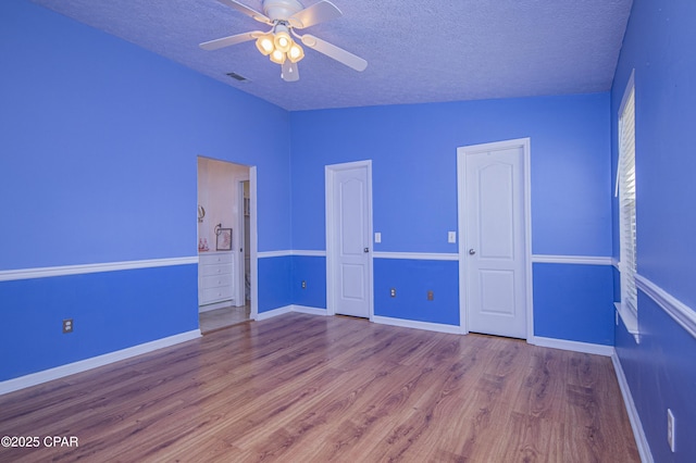 empty room featuring baseboards, a textured ceiling, a ceiling fan, and wood finished floors