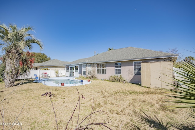 back of house featuring a fenced in pool, roof with shingles, a yard, a fenced backyard, and stucco siding