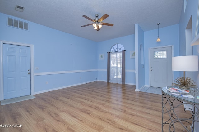 entrance foyer with a ceiling fan, visible vents, light wood finished floors, and a textured ceiling