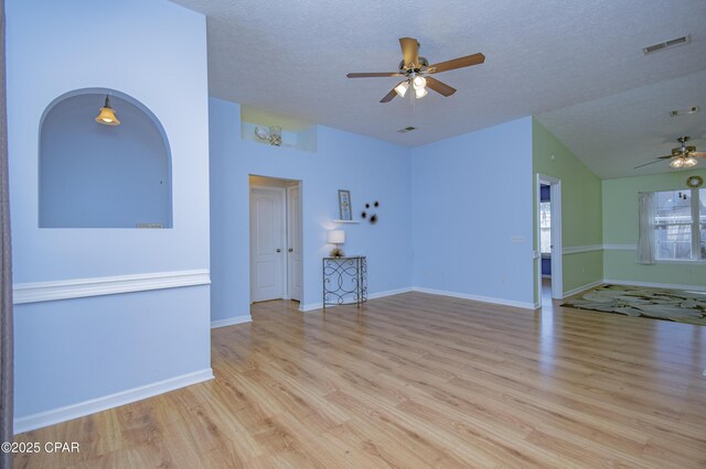 unfurnished living room featuring visible vents, baseboards, wood finished floors, a textured ceiling, and a ceiling fan