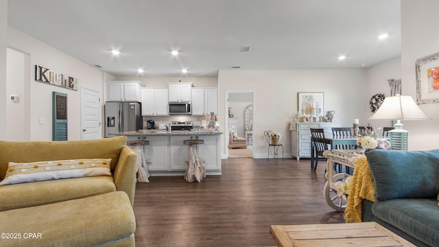 living area featuring recessed lighting, visible vents, baseboards, and dark wood-style flooring