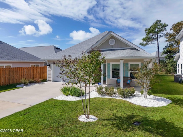 view of front of house with fence, covered porch, concrete driveway, a front lawn, and board and batten siding