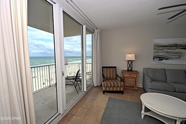 10811 Front Bch Unit 501, Panama City Beach, FL 32407 - living area with view of water and beach, ceiling fan, light tile patterned floors, and a textured ceiling