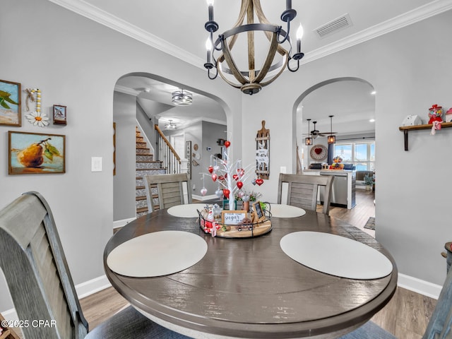 dining area featuring crown molding, stairway, wood finished floors, and visible vents